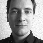 Nikolaus Hollermeier Schwarz-weiß Porträt eines Mannes mit kurzen Haaren, blauen Augen und einem neutralen Gesichtsausdruck, in einem Hemd.
