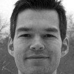 Matthias Moehl Porträt eines Mannes mit kurzem, dunklem Haar und freundlichem Lächeln, vor unscharfem, winterlichem Hintergrund.