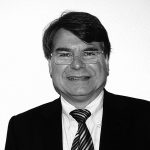 Prof. Ulrich von Alemann Porträt eines Mannes mit Brille, dunklem Anzug und gestreifter Krawatte vor einer hellen Wand.