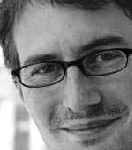 Jakob Lempp Porträt eines lächelnden Mannes mit Brille und kurzem, dunklem Haar, vor unscharfem Hintergrund.