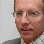 Karl-Rudolf Korte Porträt eines Mannes mit Brille, blonden Haaren, in einem grauen Anzug und karierten Hemd, vor einem hellen Hintergrund.
