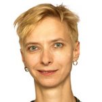 Halina Wawzyniak Porträt einer Person mit kurzen blonden Haaren und Ohrhängern, vor einem weißen Hintergrund.