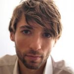 Daniel März Porträt eines Mannes mit braunen Haaren und Bart, der direkt in die Kamera schaut. Helle Hintergrundbeleuchtung.