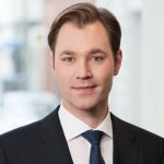 Julius van de Laar Porträt eines Mannes mit kurzen, braunen Haaren, in einem Anzug mit Krawatte, vor einem unscharfen Hintergrund.