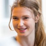 Josephine Witt Porträt von Josephine Witt, einer politischen Aktivistin, mit lächelndem Gesicht und langen, lockigen Haaren.