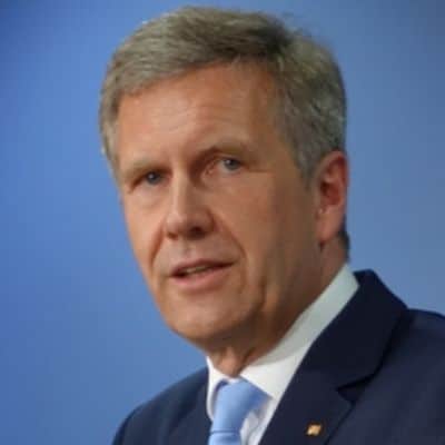 Porträt von Christian Wulff in Anzug mit hellblauer Krawatte, lächelnd vor einem neutralen Hintergrund.