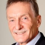 Peter Walschburger Porträt eines älteren Mannes mit kurzem, grauem Haar und Schnurrbart, trägt ein schwarzes Jackett und ein helles Hemd.