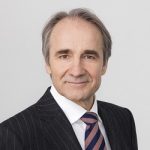 Karl-Heinz Streibich Porträt eines Mannes mit grauen Haaren, Anzug und Krawatte, vor einem hellen Hintergrund.