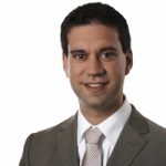 Martin Schorn Porträt eines Mannes in Anzug mit Krawatte, lächelnd vor weißem Hintergrund.