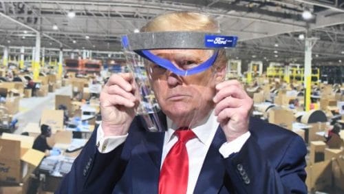 Bei der Besichtigung der Ford-Fabrik im Mai in Ypsilanti hält US-Präsident Donald Trump ein Gesichtsvisier hoch. Mundschutz trug Trump trotz Aufforderung nicht. Er wolle der Presse keine "Freude" machen. (c) Daniel Mears/Detroit News/TNS via ZUMA Wire