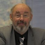 Eckhard Jesse Porträt von Prof. Dr. Eckhard Jesse mit Brille, Bart und Anzug, lächelnd vor unscharfem Hintergrund.