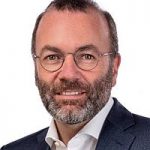 Manfred Weber (CSU) Porträt eines Mannes mit Brille und Bart, lächelnd, in einem Anzug vor einem weißen Hintergrund.
