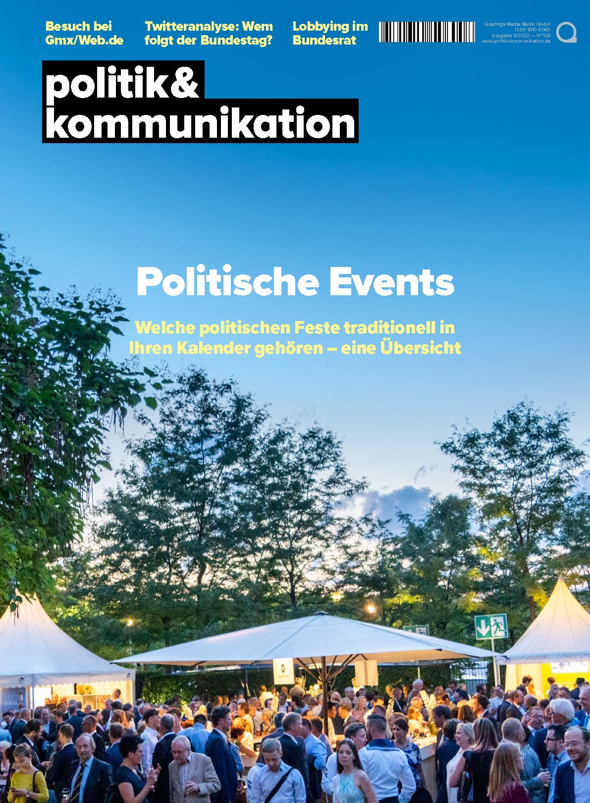 Menschenmenge auf einem politischen Event unter freiem Himmel, umgeben von Bäumen und Ständen bei Dämmerung.