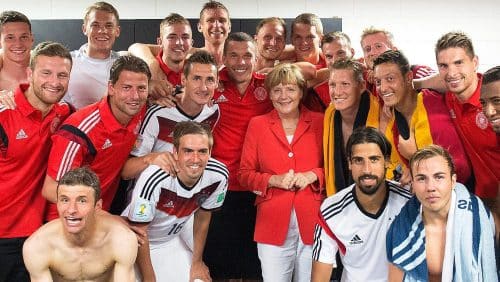 Die damalige Bundeskanzlerin Angela Merkel (CDU) besucht die deutsche Fußballnationalmannschaft nach dem Auftaktsieg gegen Portugal bei der WM 2014 in Salvador, Brasilien in der Kabine. (c) picture alliance/dpa/Guido Bergmann