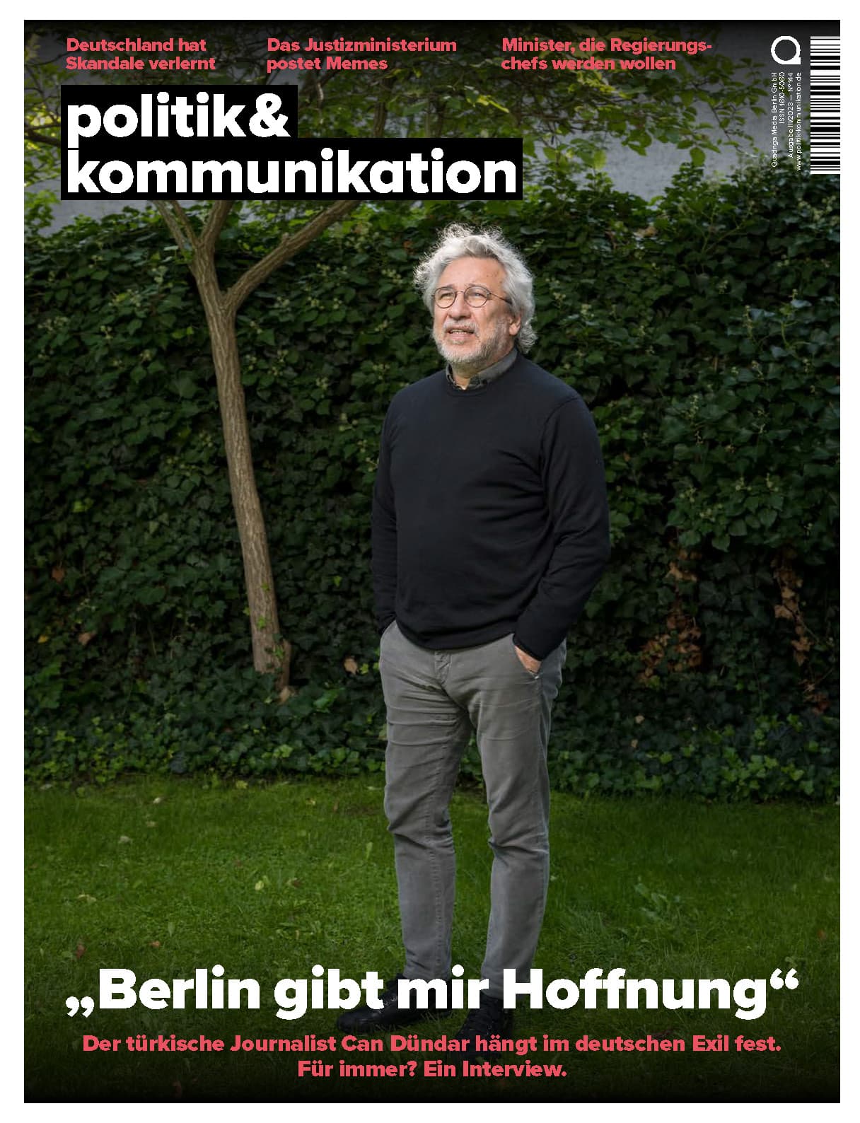 Mann mit grauen Haaren steht in einem Garten, trägt einen grauen Pullover und schaut in die Kamera.