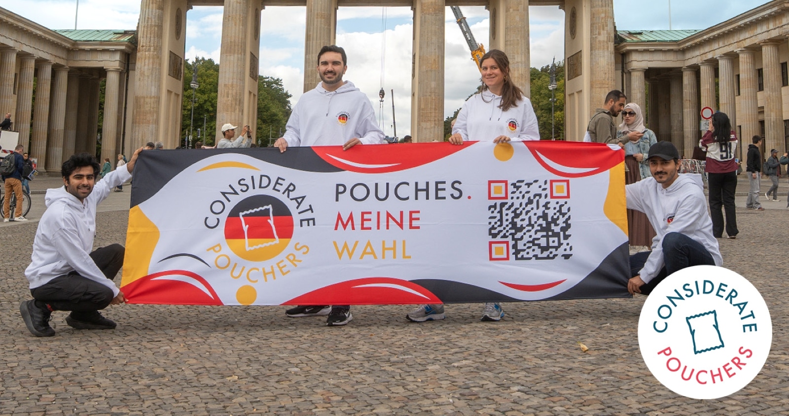 Vier Personen halten ein Banner mit der Aufschrift "Considerate Pouches. Pouches. Meine Wahl" vor einem historischen Gebä...