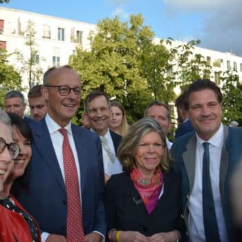 Gruppe von Menschen lächelt in einer städtischen Umgebung, umgeben von Bäumen und Gebäuden.