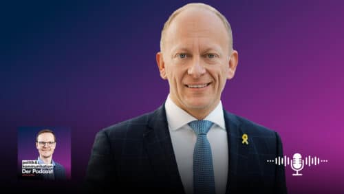 Porträt eines lächelnden Mannes in Anzug vor einem lila Hintergrund, mit Podcast-Logo und Mikrofon-Symbol.