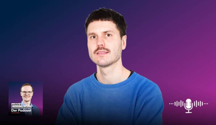 Mann mit Schnurrbart in blauer Kleidung vor einem lila Hintergrund, Podcast-Logo links unten.