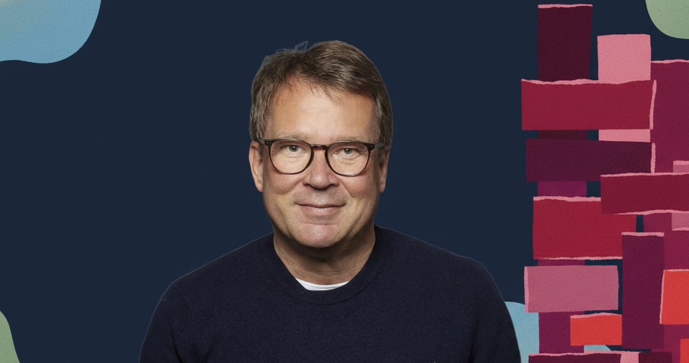 Michael Wedell. Foto: Laurence Chaperon Porträt eines Mannes mit Brille, lächelnd vor einem bunten, abstrakten Hintergrund.