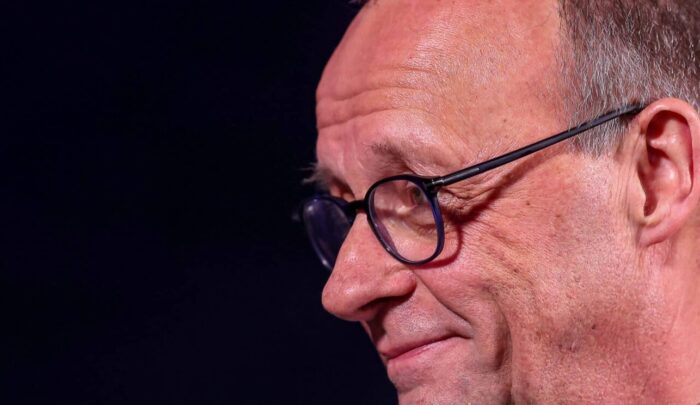 Profilansicht eines lächelnden Mannes mit Brille, vermutlich ein Politiker, während eines Handball-Finales in Herning.