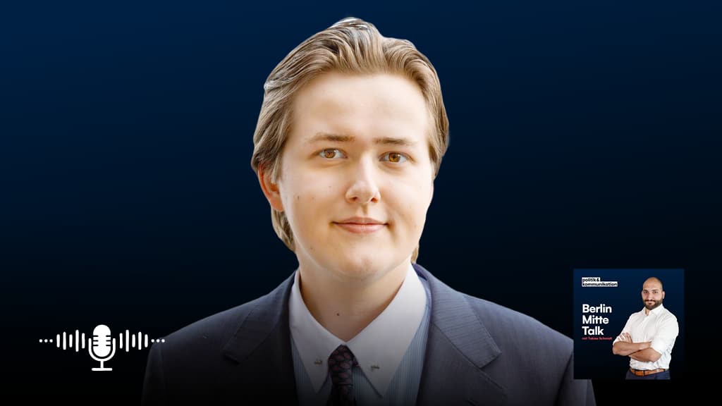 Podcast-Banner mit einem Mann in Anzug vor dunklem Hintergrund, Mikrofon- und Podcast-Logo-Elementen.