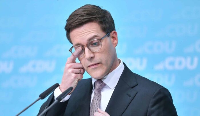 Manuel Hagel in Anzug, hält eine Hand an seine Brille, spricht bei Pressekonferenz im Konrad-Adenauer-Haus, CDU-Logo im H...