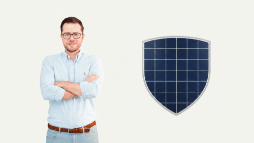 Man in a blue striped shirt with arms crossed, standing beside a large solar-panel shield on a light background.