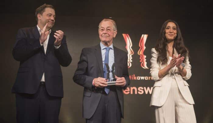 Drei Personen applaudieren auf der Bühne bei der Verleihung des Politikawards 2026. Hintergrund mit Logo des Events.