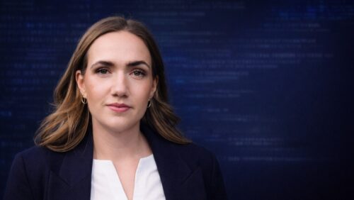 Porträt einer Frau mit langen, braunen Haaren, die in die Kamera schaut, vor einem Hintergrund mit digitalem Code.