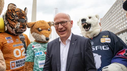 Kai Wegner steht lächelnd mit Sportmaskottchen in Berlin beim Berliner Hoffest 2026.