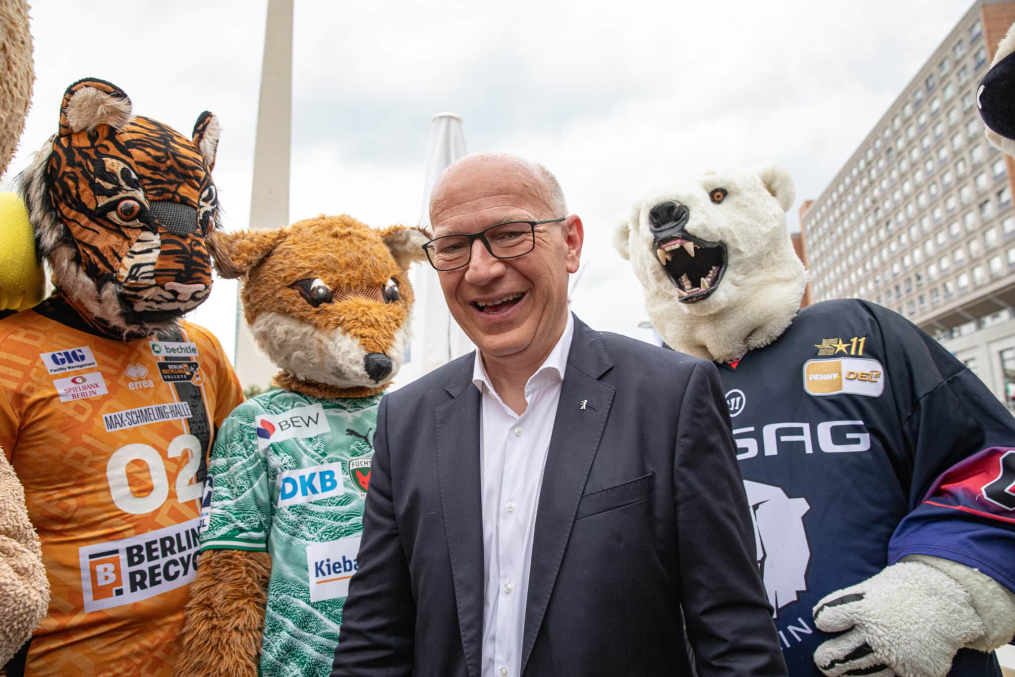 Kai Wegner steht lächelnd mit Sportmaskottchen in Berlin beim Berliner Hoffest 2026.